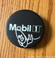 Top side of the hockey puck showing the Mobil 1 logo and Doug Gilmour's signature in silver.