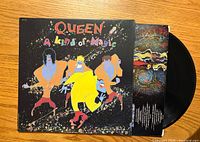 Front cover of Queen's 'A Kind of Magic' vinyl record album with colorful cartoon illustrations of band members.