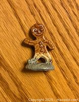 Front view of a small ceramic glazed gingerbread man figurine with smiling face and button details.
