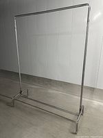 Full view of the metal clothing rack showing the rectangular base, vertical supports, and horizontal hanging bar.