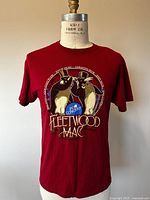 Front view of maroon t-shirt showing graphic of two rabbits in top hats and Fleetwood Mac logo.
