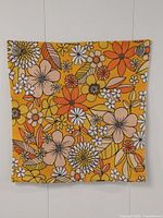 Full view of the front of the vintage daisy floral pillowcase showing the full colorful pattern in orange, yellow, beige, white, and brown on a woven fabric.