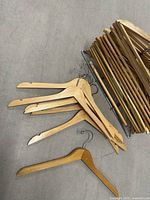 Close-up photo showing a pile of old wooden hangers stacked on the floor beside the chrome hanger stand.