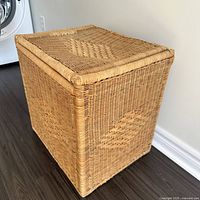 Full front angle of the vintage rattan laundry hamper showing woven texture and rolled rim lid.