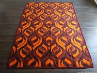 Top-down view of full bedspread showing bright orange and brown geometric pattern.