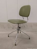 Front view of vintage avocado green swivel desk chair with chrome steel base showing seat and backrest.