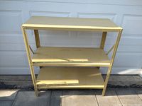 Front view of the low yellow metal shelf unit with three shelves.