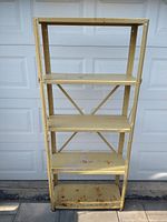 Front view of the metal shelving unit showing four shelves with minor rust and dents.