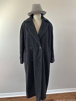 Full view of vintage long charcoal wool and llama overcoat on mannequin, double-breasted with side pockets and cuff strap detail.