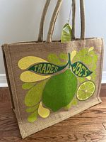 Side view of the Trader Joe's tote bag showing the citrus fruit design on natural jute fabric and one side handle.