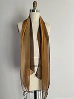 Front view of sheer ombré orange to brown scarf displayed on mannequin, showing length and color gradient.