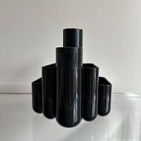 Front view of the black plastic Deco inspired desk organizer showing the large central compartment and smaller side compartments.