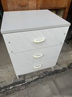 Front view of white retro three drawer storage unit showing all three drawers and white handles.
