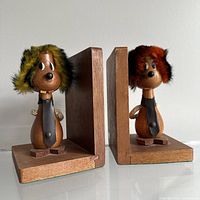 Pair of teak wood bookends shown side by side, each with carved dog figure and fur hat, viewed at front angle