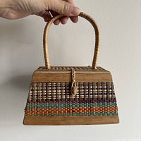 Full front view of the vintage wooden purse showing its trapezoid shape, woven pattern, wooden trim, and handle.