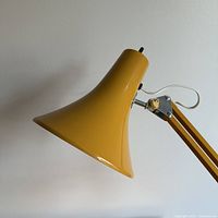 Close-up of the yellow metal lampshade and part of the articulating arm showing the shape and color.