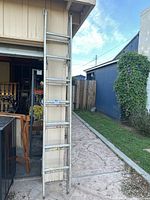 Full view of the aluminum extension ladder standing upright against a wall, showing the overall condition and structure