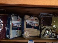 Two twin Polartec blankets in packaging - beige and blue - along with two plush throws including animal print and burgundy. Items appear mostly new in packaging.