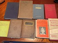 Eight vintage books including the first edition of Gone with the Wind spread on a wooden table.