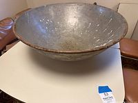 Front view of a large metal mixing bowl showing worn interior and rusted rim