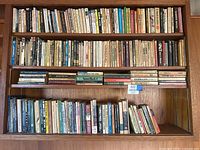 View of multiple shelves filled with a large collection of vintage paperback novels and some dictionaries in various genres.