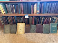 Books on multiple wooden shelves showing a large assortment of vintage and antique hardcover books with varied bindings and titles.
