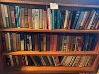 Three wooden shelves filled with vintage hardcover and paperback books with spines showing titles on psychology, nutrition and health, social case work, and related topics