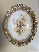 Top angled view of vintage porcelain bowl showing detailed floral design and gold scalloped rim with pink accents.