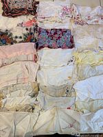 Group of vintage women's handkerchiefs in various colors and embroidered floral patterns, some with lace edges.