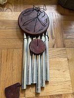 Top and front view of the wind chime showing the wooden circular top with wire decoration and metal tubes.