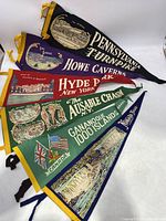 Full view of 6 felt souvenir pennants arranged overlapping to show titles and designs