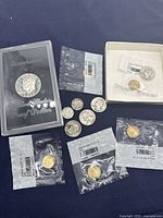 Photo showing the 1971 Eisenhower Proof Dollar in a clear impact-resistant plastic case with 'United States Proof Dollar' text and stars, several loose pre-1967 silver coins, and four sealed Ireland gold-plated 1/2 penny coins.