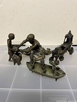 Grouping of three metal ethnic figurines shown together from an elevated angle on a clear plastic surface.