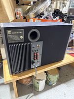 Full rear and side view of the Morel SoundSub IS-9A subwoofer showing amplifier fins, bass reflex port, connection terminals, and power cable plugged in.