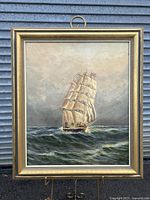 Full frontal view of framed oil painting depicting a three-masted sailing ship at sea.