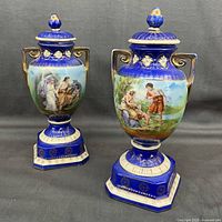Pair of cobalt blue porcelain urns with lids, displayed front angle showing full height and bases