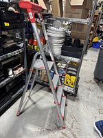 Full view of lightweight aluminum step stool ladder with three steps and red plastic top.