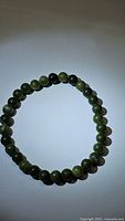 Front view of stretchy green jade bead bracelet, showing uniform round beads in various green shades.