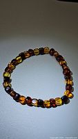 Front view of natural Baltic amber stretchy bracelet showing gradient of bead colors, from yellow to dark amber.