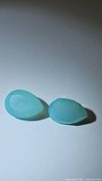 Two pear cut light Arctic blue chalcedony gemstones shown on white background under direct light, highlighting their translucent quality and blue hues.