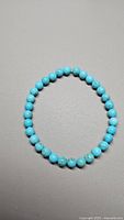 Photo showing the full circular turquoise bead bracelet laid flat on a neutral surface.
