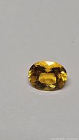 Natural golden yellow oval cut Helidor gemstone placed on white background showing cut and clarity.