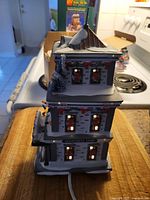 Side view of the department store building showing the three floors with lit windows, snowy roof, and Christmas decorations.