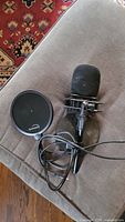 Photo showing one handheld microphone with foam windscreen on shock mount and detachable pop filter with cable.