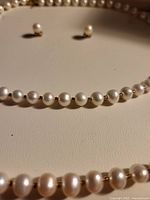 Close-up view of the pearl necklace, bracelet, and earrings showing the pearl and gold spacer bead arrangement.