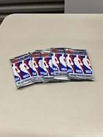 Five sealed packs of NBA Hoops 1990 trading cards displayed on a flat surface.
