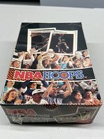Front view of sealed 1991-92 NBA Hoops wax box showing Dominique Wilkins and Clyde Drexler player cards and cheering crowd background.