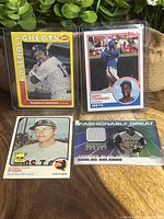 Four baseball cards shown together on wood surface: Munson, Strawberry, Fisk, Delgado jersey card.