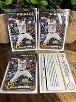 Set of 4 Paul Skenes Rookie Cards in protective sleeves, showing front and back of one card with clear labels and Pittsburgh Pirates uniform.