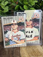 Photo showing two Billy Ripken 1989 Fleer baseball cards; one in plastic with obscenity on bat knob covered by tape and one standard card in front.